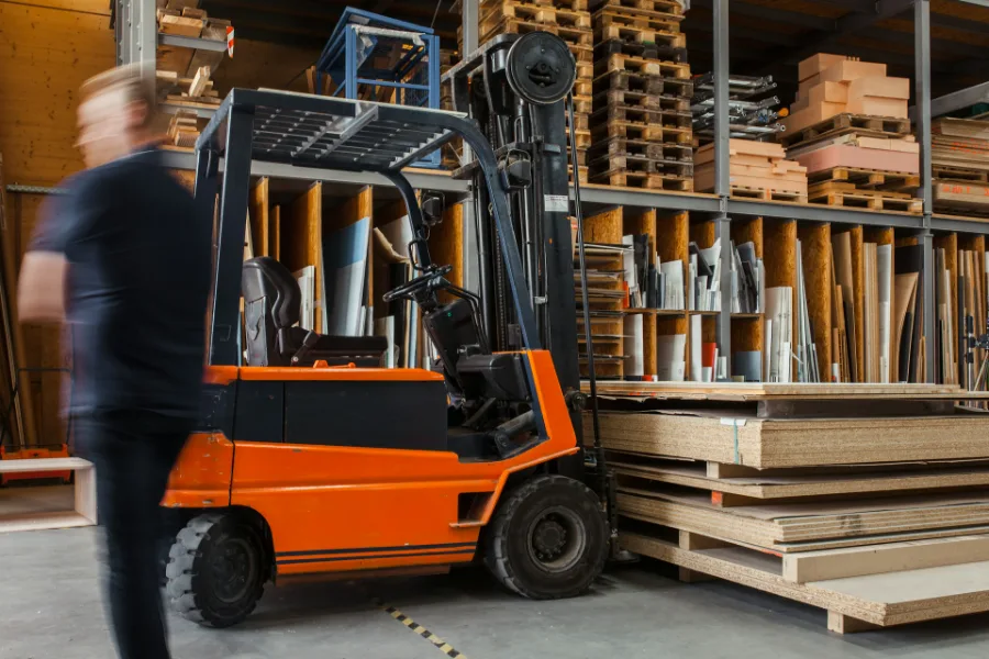 Warehouse operative moving pallets of stock with a forklift