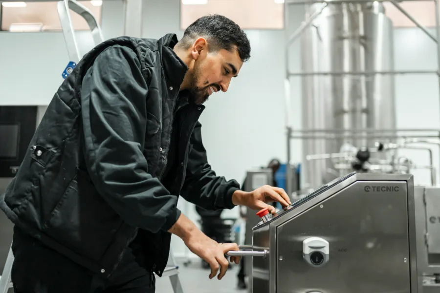 Production technician operating processing equipment on a factory floor