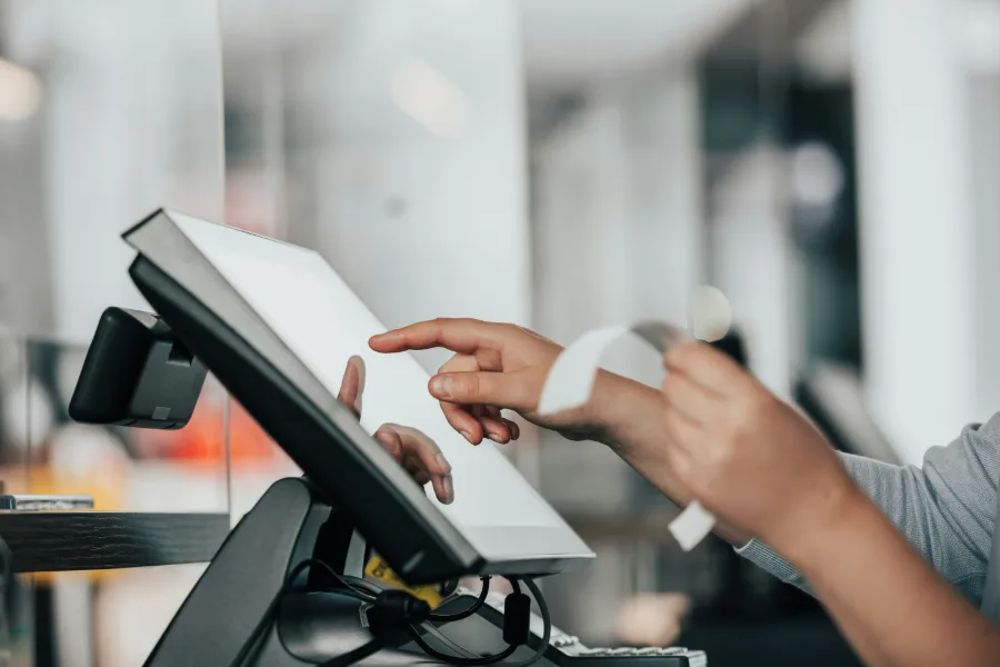 Hands entering a transaction on a counter terminal, receipt printing
