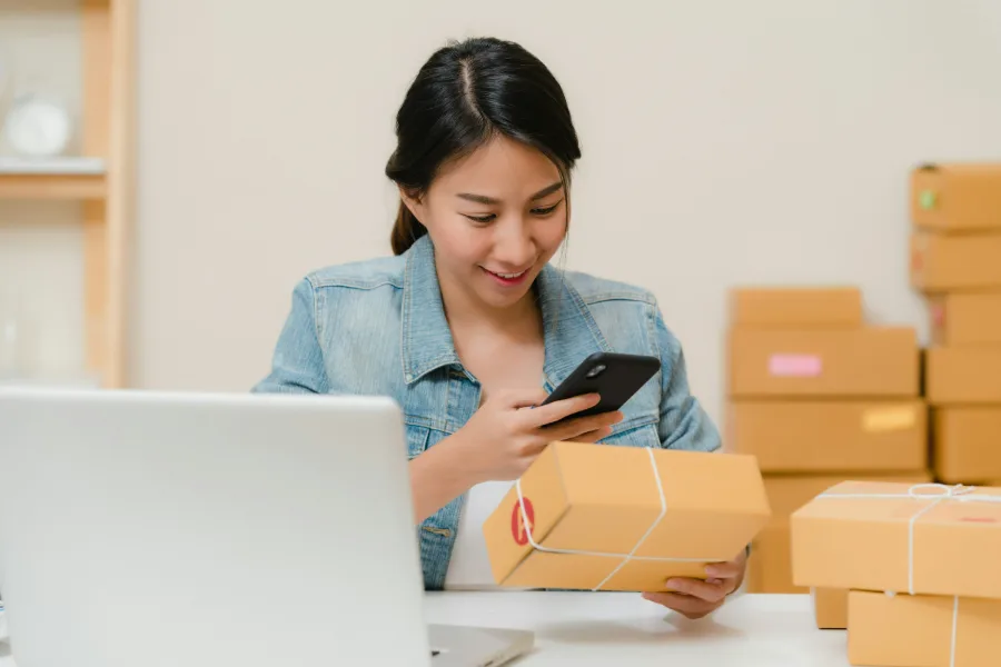 Business owner confirming a customer order beside packed parcels